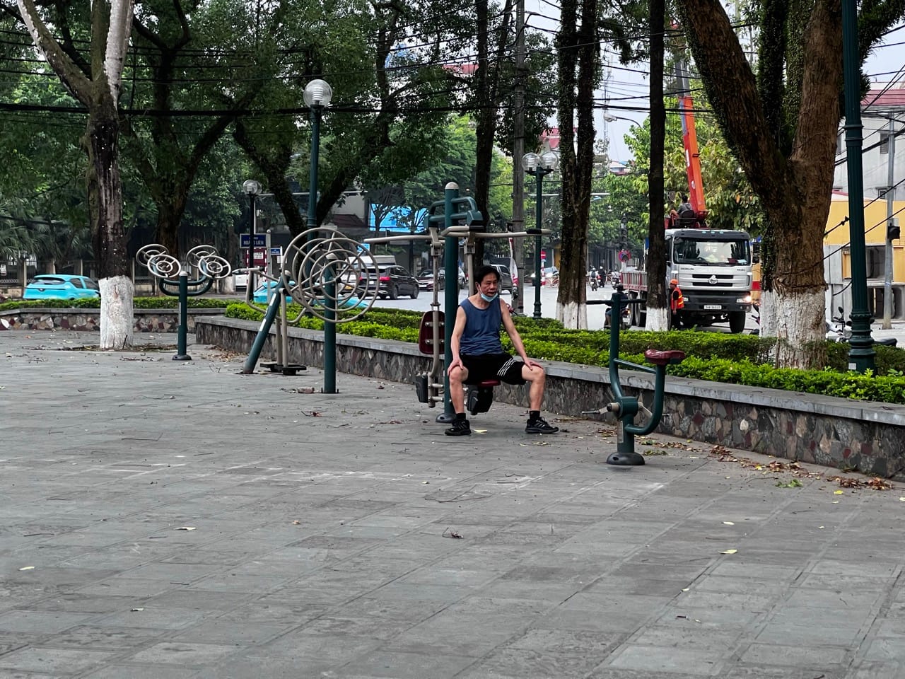 elderly Vietnamese man exercising on outdoor gym equipment in a Lao Cai park