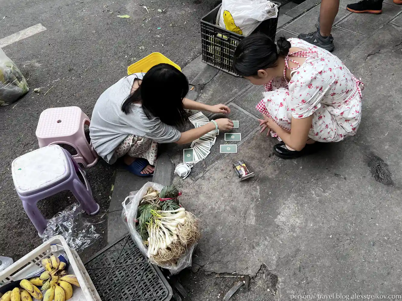 Girls arrange tarot on the sidewalk of a market in Hekou, China.
