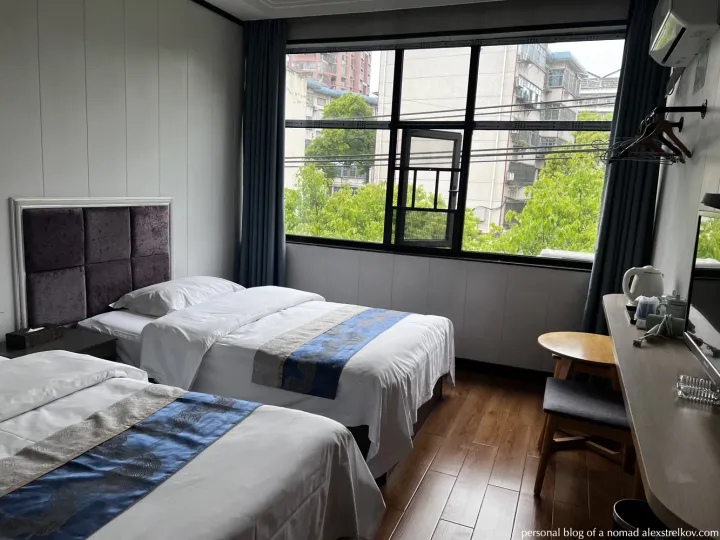 Twin room at Huaihua Jiaxing Boutique Hotel 怀化嘉兴精品酒店 — two beds, large window, green trees outside